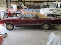 Maroon convertible car with a tan top, parked in a garage.