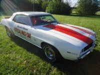 White convertible car with red racing stripes, parked on grass.