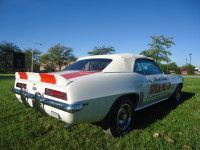 White and red classic Camaro convertible on grass, sunny day.