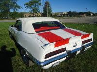 White convertible car with red racing stripes, parked on grass.