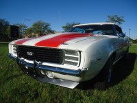 White and red 1969 Chevrolet Camaro SS convertible on green grass under a blue sky.