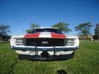 White and red 1969 Chevrolet Camaro SS muscle car, black grill, on grass.