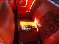 Red car interior with bucket seats, seatbelts, and detailed textured fabric.