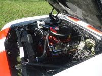 Car engine compartment, black engine, chrome accents, red air filter, white and orange body.