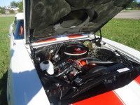 White classic car with open hood, red stripe, and engine details visible.