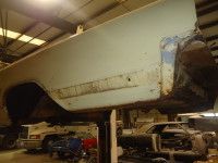 A car's damaged rear panel is being worked on in a repair shop.