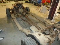 Car chassis with engine and wheels in a garage.