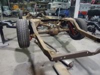 Rusty car frame with wheels in a workshop.