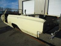 Yellow convertible car body frame in a garage.