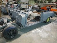 Partially disassembled light blue classic car in a workshop.