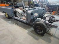 Partially assembled classic convertible car in a workshop. Gray body, black wheels.