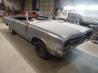 Gray convertible car in a garage, undergoing restoration.