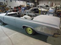 Classic blue convertible car in a workshop, undergoing restoration.