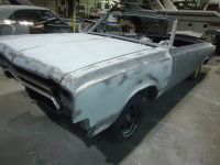 Partially restored, grey convertible car in a garage, bodywork done, ready for paint.