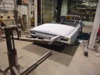 Car being worked on in a garage; a lift supports the vehicle.