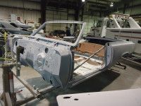 Partially disassembled classic car, light blue color, in a workshop.