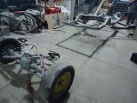 Car parts in a garage, including a wheel, frame, and other disassembled components.