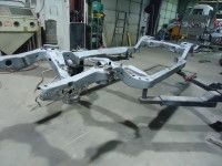 Gray car chassis in a workshop setting.