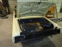 Open trunk of a white classic car. The trunk is empty except for some items in boxes.