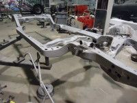 Gray car chassis in a workshop setting.