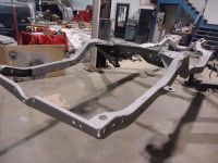 Gray car chassis in a workshop setting.