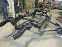 Black car chassis components on a shop floor.