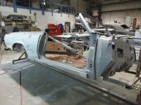 Partially disassembled light blue classic car in a workshop.