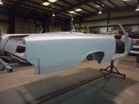 Partially assembled classic car body in a workshop.