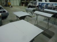 Car parts on sawhorses in a workshop, ready for painting.