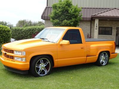 Blue convertible Corvette parked on pavement. Chrome details, black convertible top.