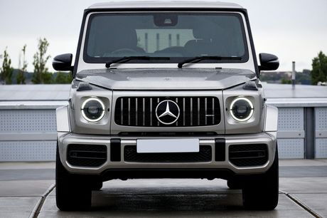 A silver mercedes benz g63 is parked in a parking lot.