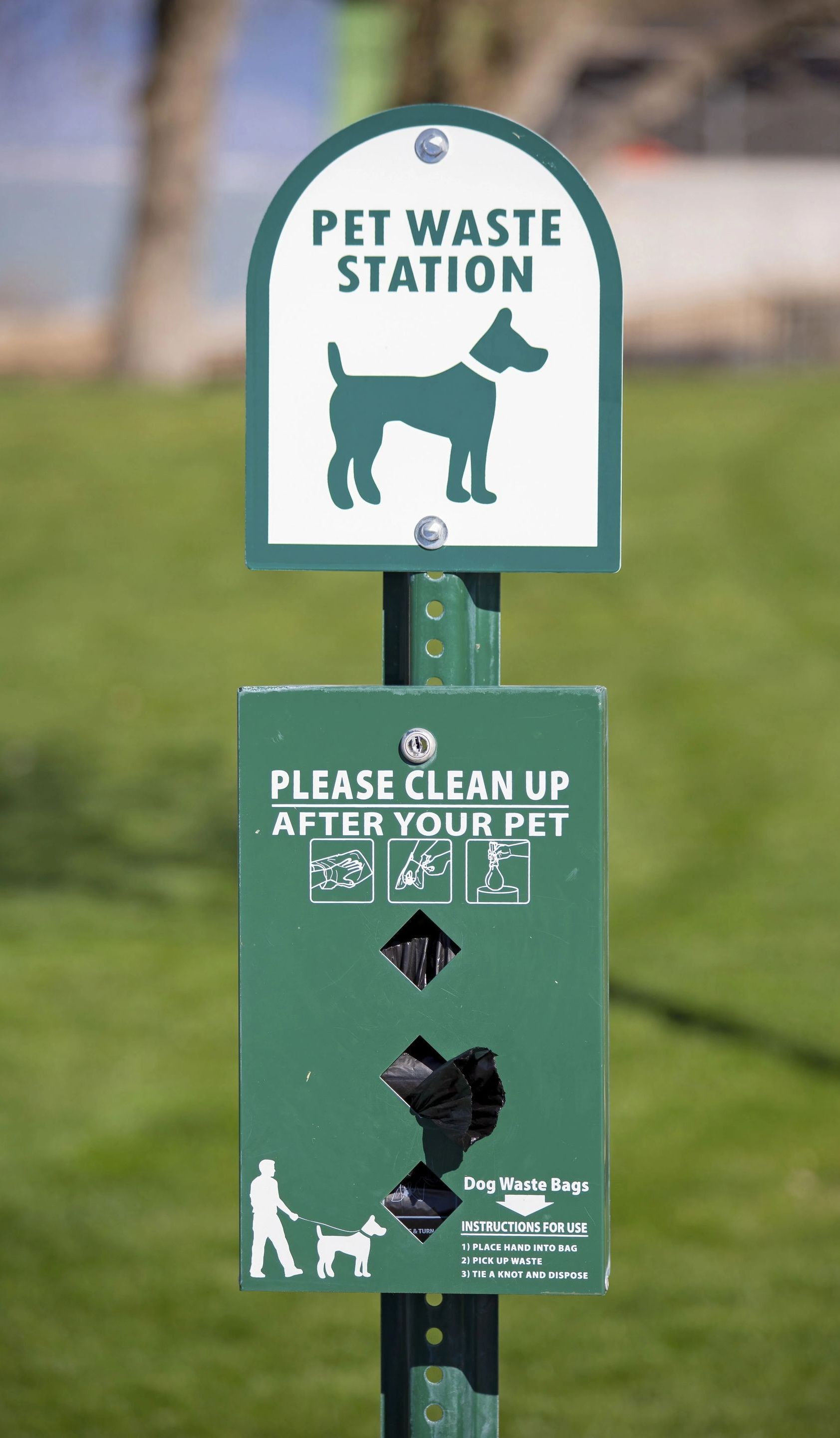 A pet waste station with a sign that says please clean up after your pet