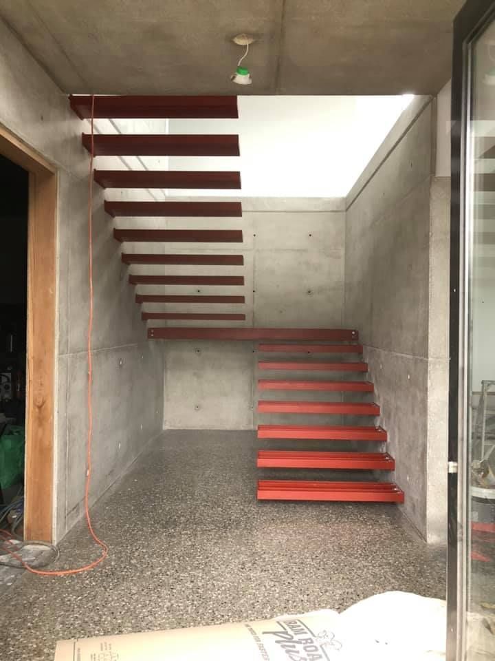 A red steel staircase structure built within concrete walls — Burke Metal Fabrication In Taree, NSW