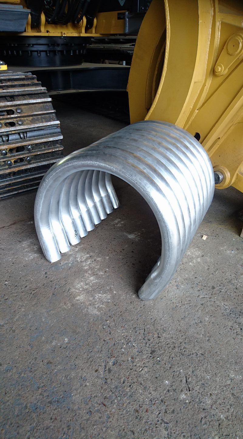 A roll of metal tubes in a semi-circle sitting on the ground — Burke Metal Fabrication In Taree, NSW
