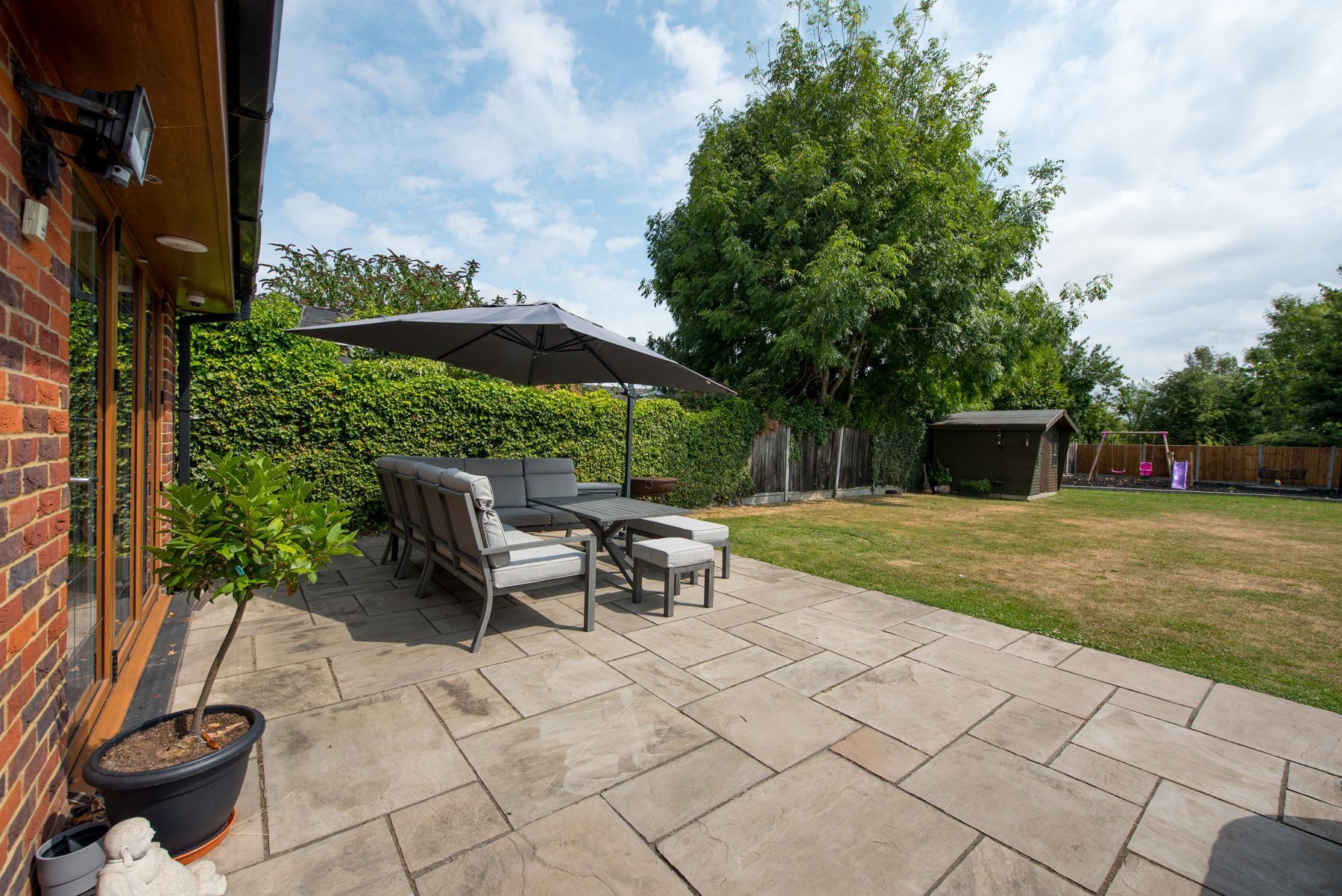 A patio with a table and chairs and an umbrella in the backyard of a house.