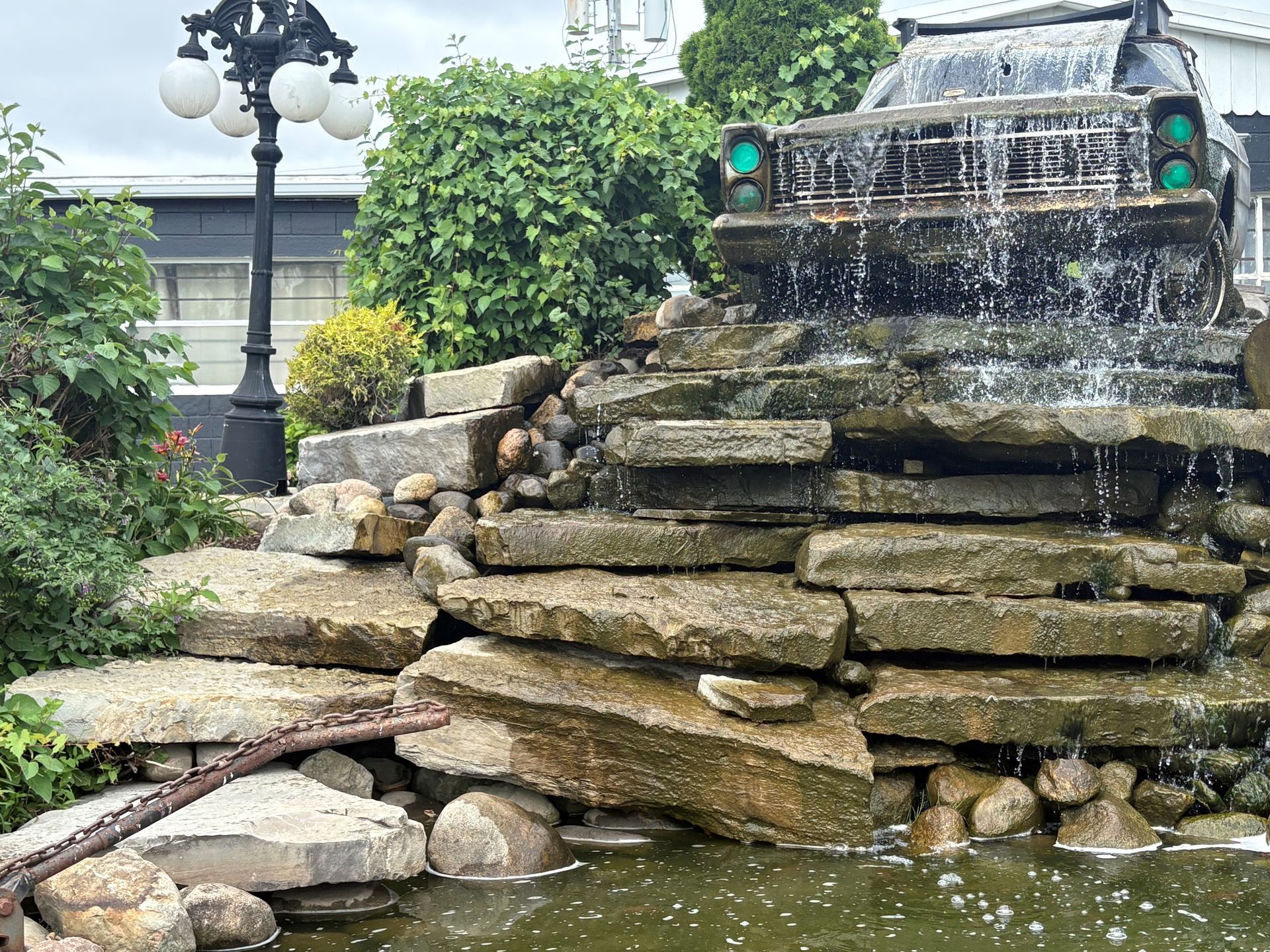A waterfall is surrounded by potted plants and rocks in a garden.