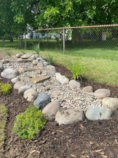 A rock garden with a chain link fence in the background.