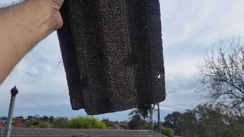 hand holding piece of damaged roof