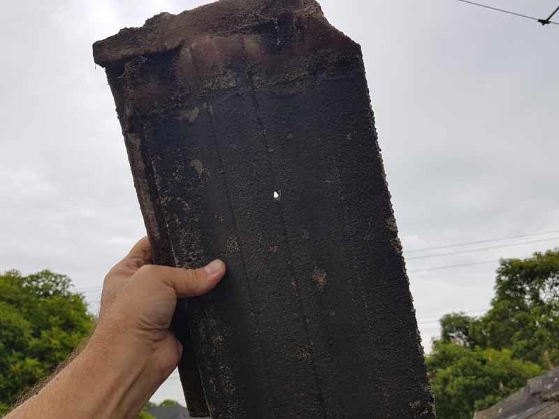 hand holding piece of damaged roof