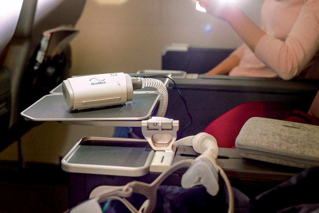 A woman is sitting on an airplane looking at her phone — Mid North Coast Sleep Clinic in Taree, NSW