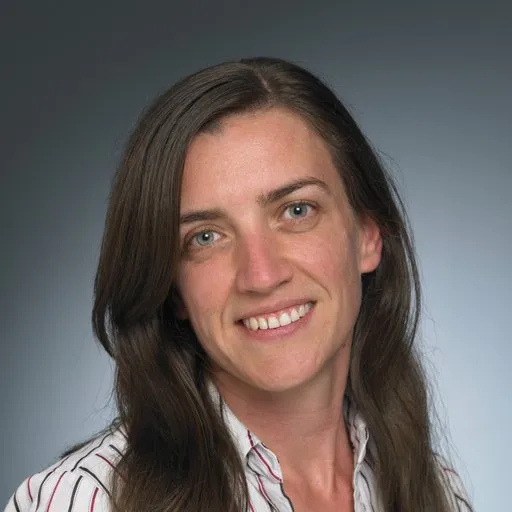 Woman with long brown hair smiling, wearing a striped shirt, on a gray gradient background. — Mid North Coast Sleep Clinic in Taree, NSW