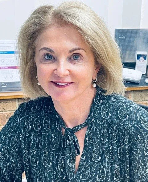 Woman with blonde hair wearing a patterned green top smiles indoors. — Mid North Coast Sleep Clinic in Taree, NSW