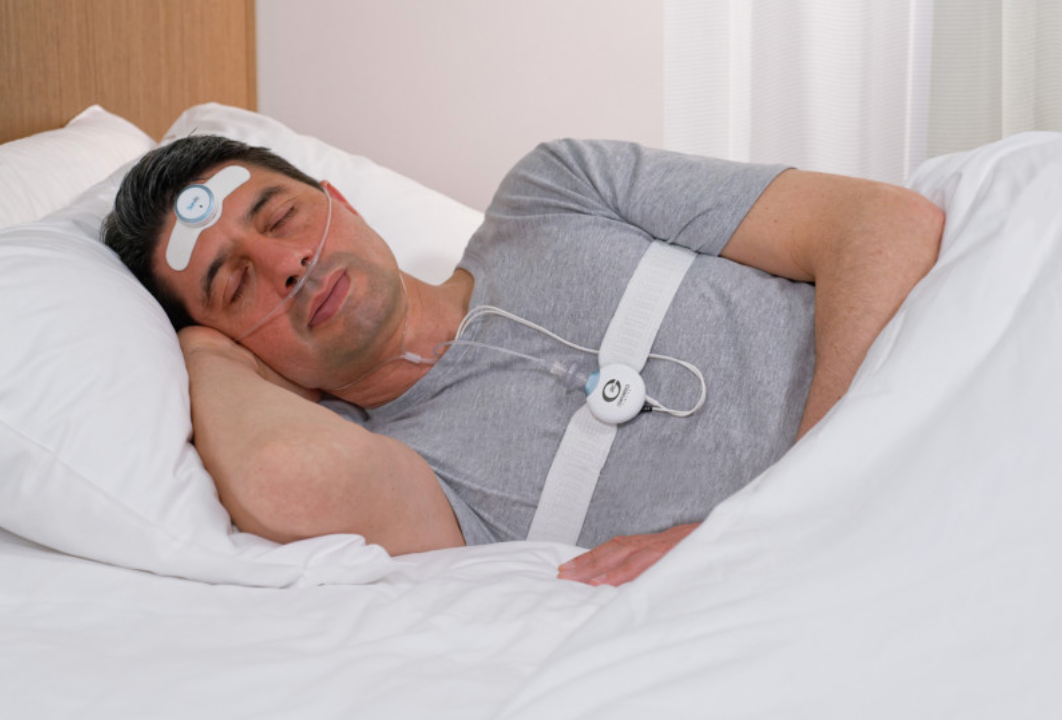 A man is sleeping in a bed with a device on his head. — Mid North Coast Sleep Clinic in Taree, NSW