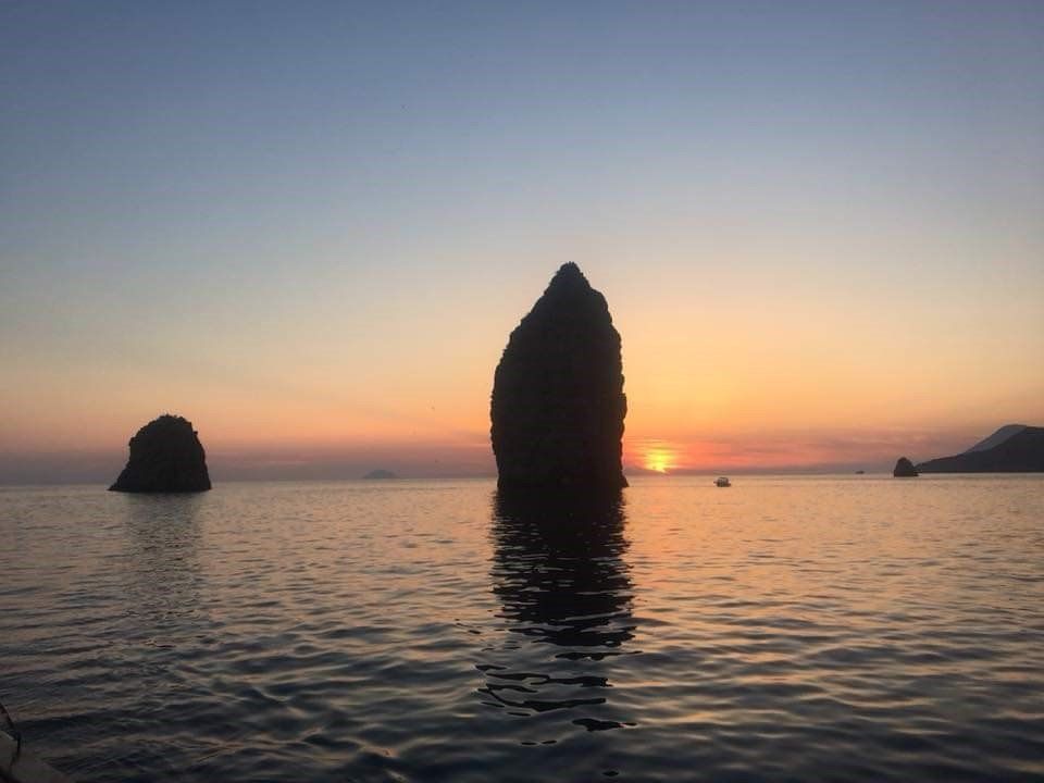 A large rock in the middle of the ocean at sunset