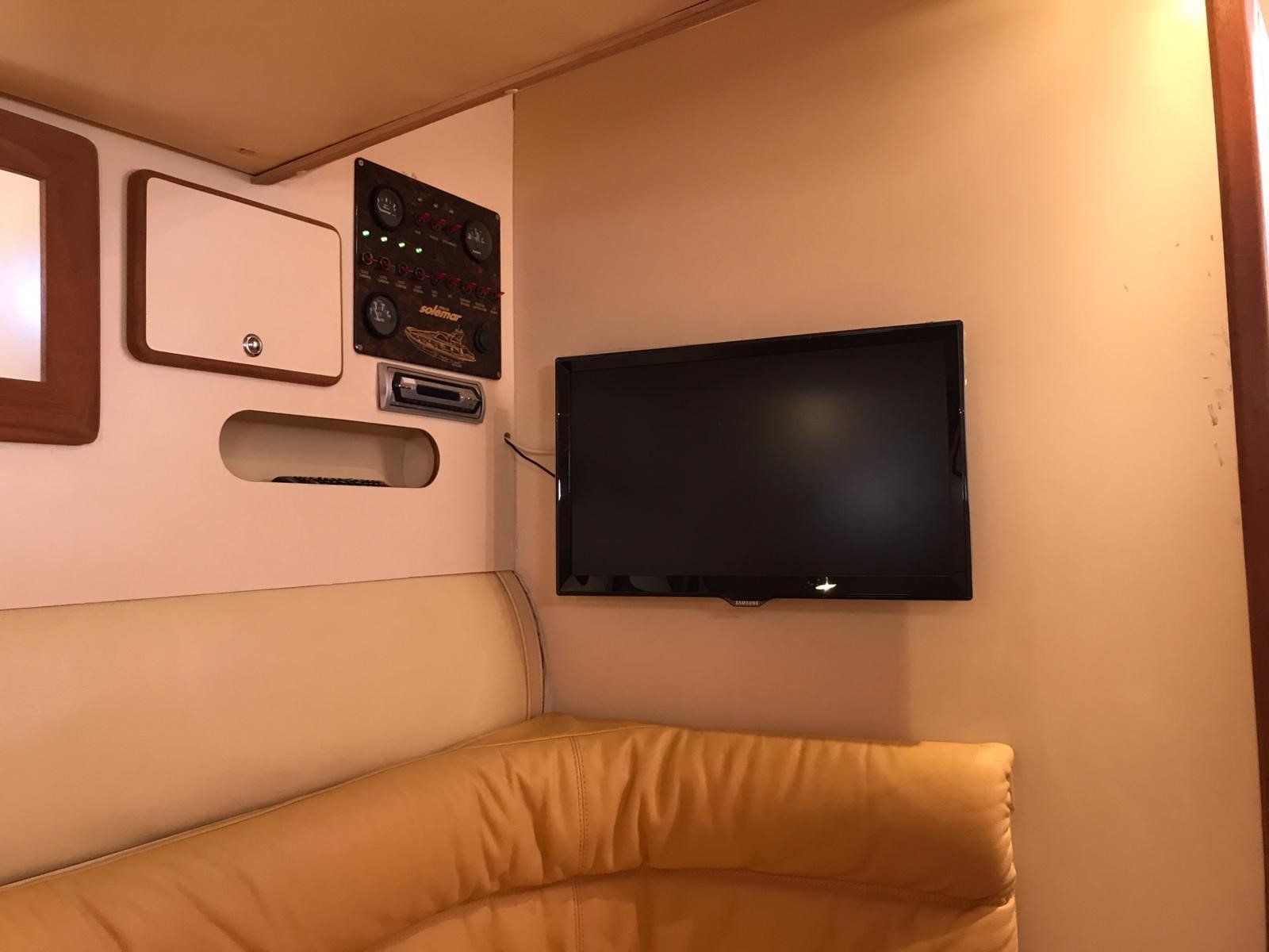 Un soggiorno con un divano e una TV a schermo piatto sulla parete.