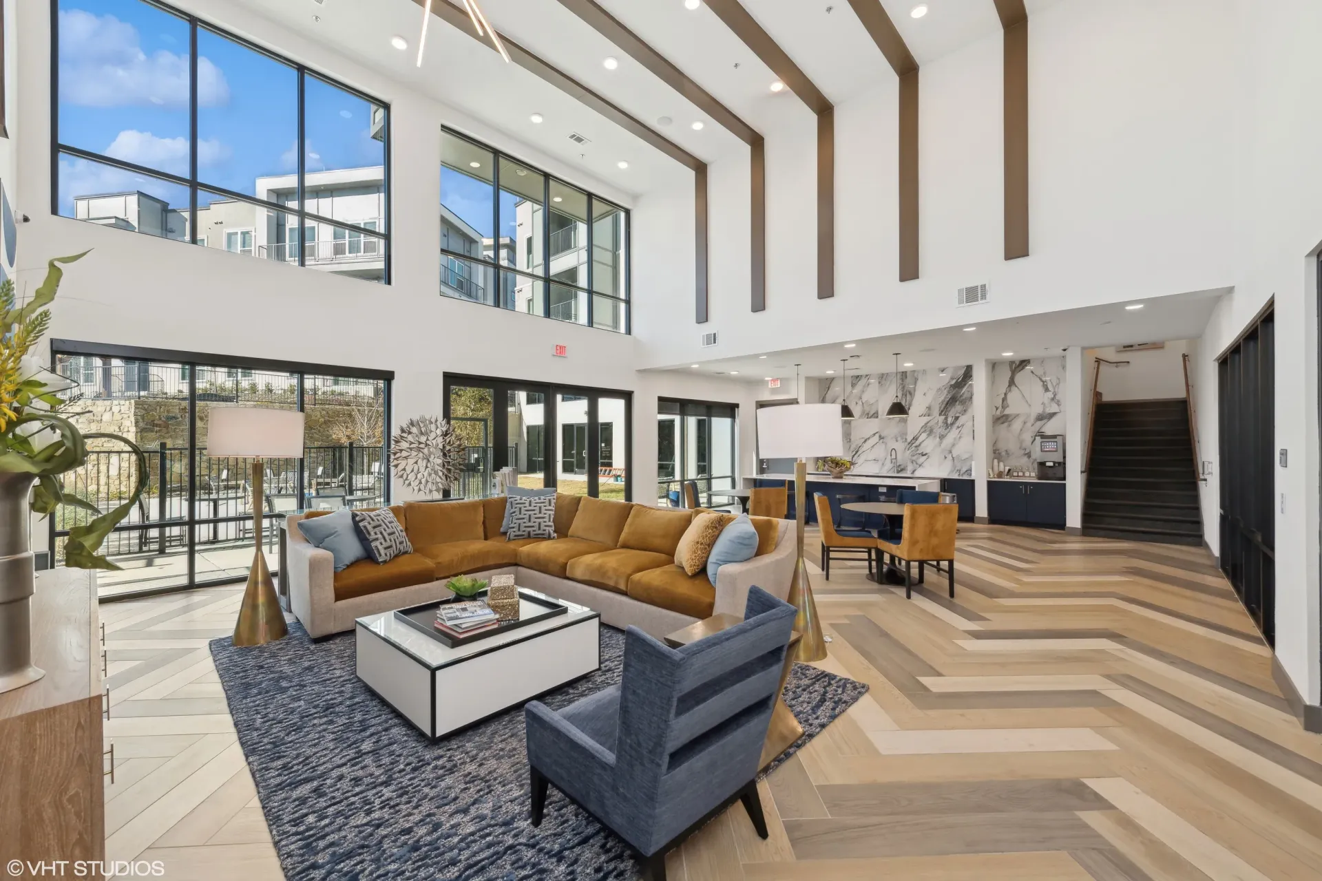 Bright two-story apartment lobby with large windows, modern seating, and marble accents.