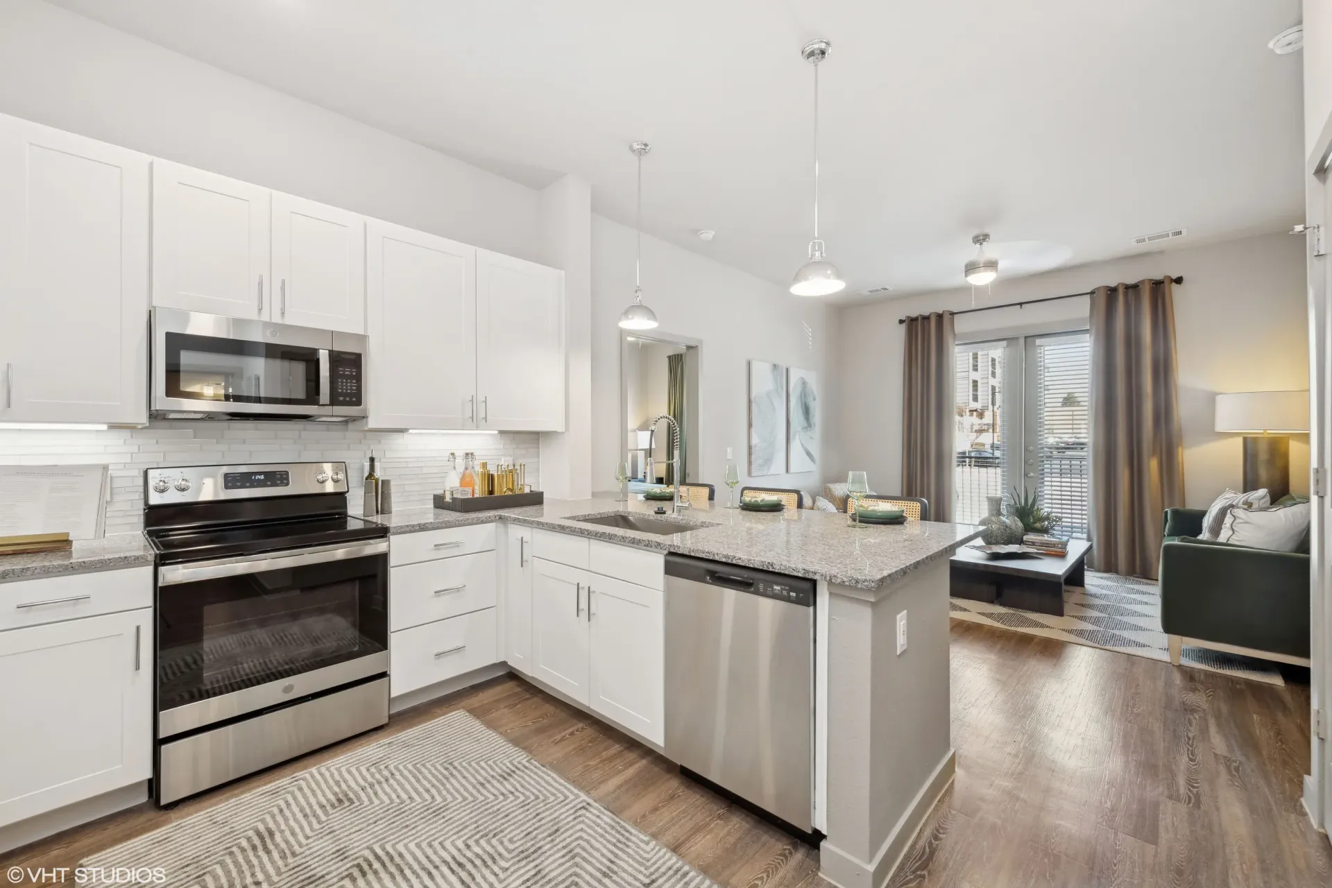 Open-concept kitchen with white cabinets, stainless steel appliances, and an island overlooking the living area.