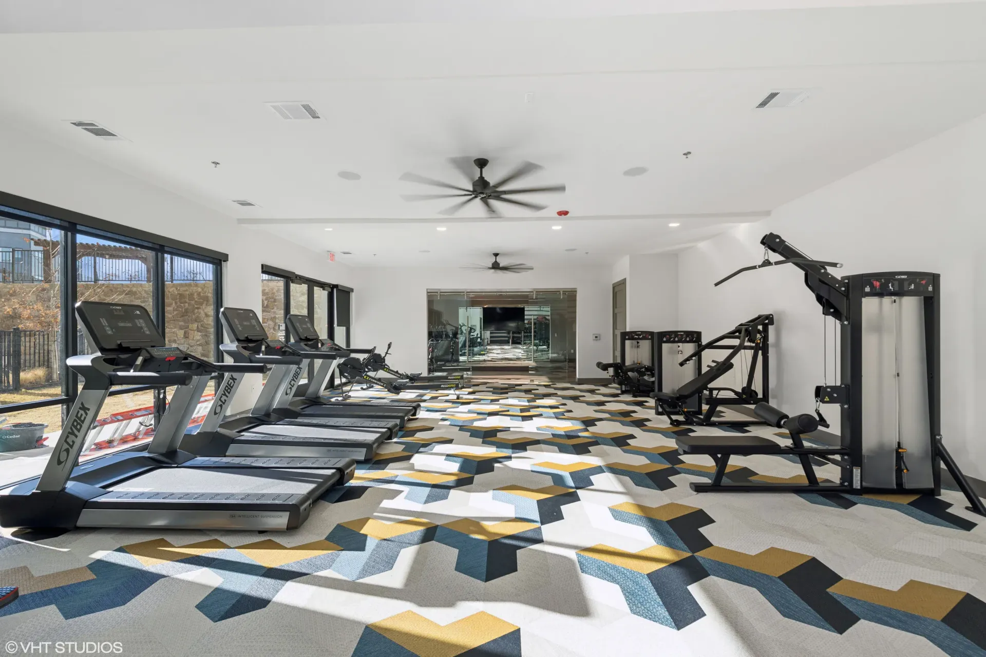 Bright community gym with treadmills and weight machines along white walls.