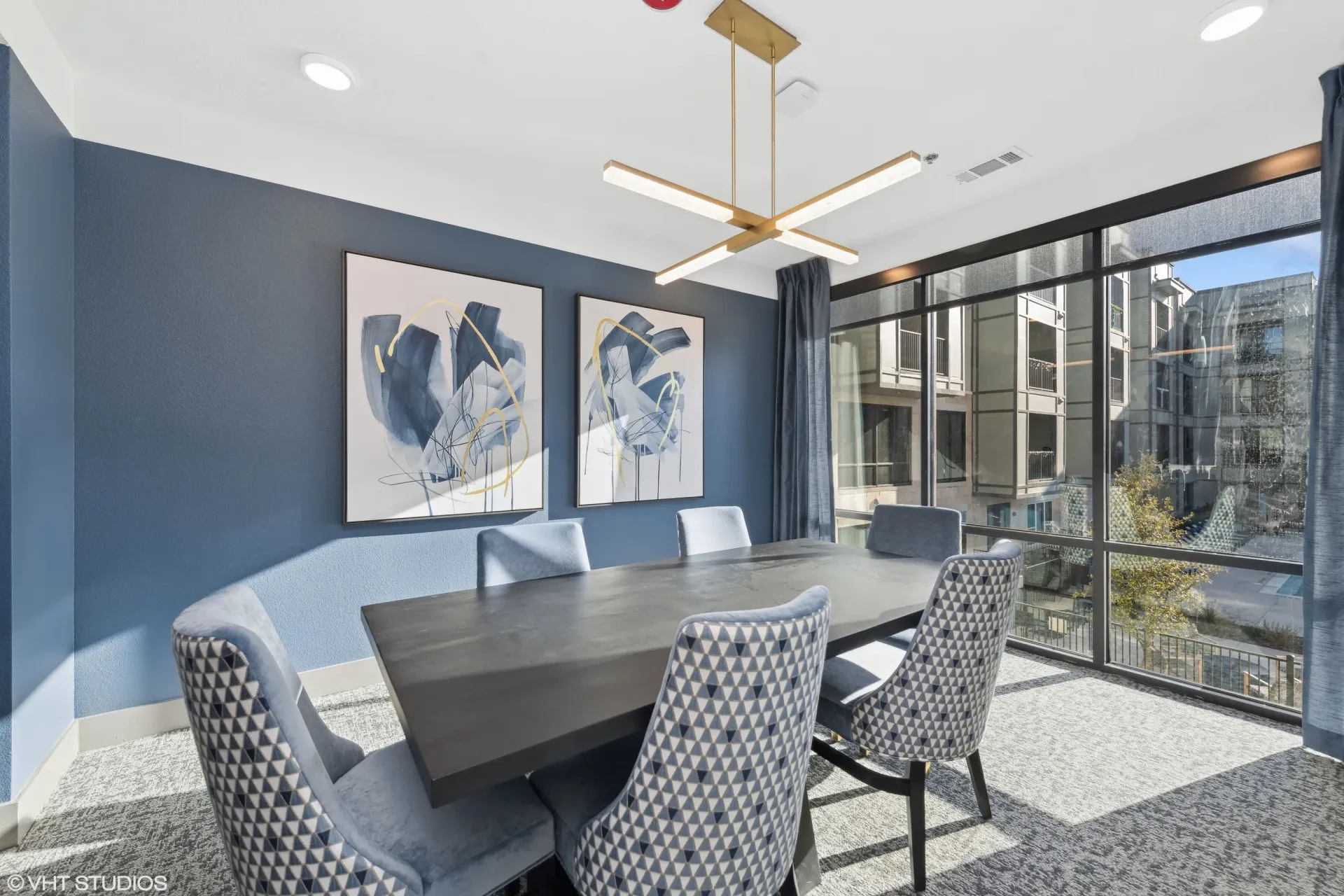 Modern resident lounge with blue wall, abstract art, and large windows.
