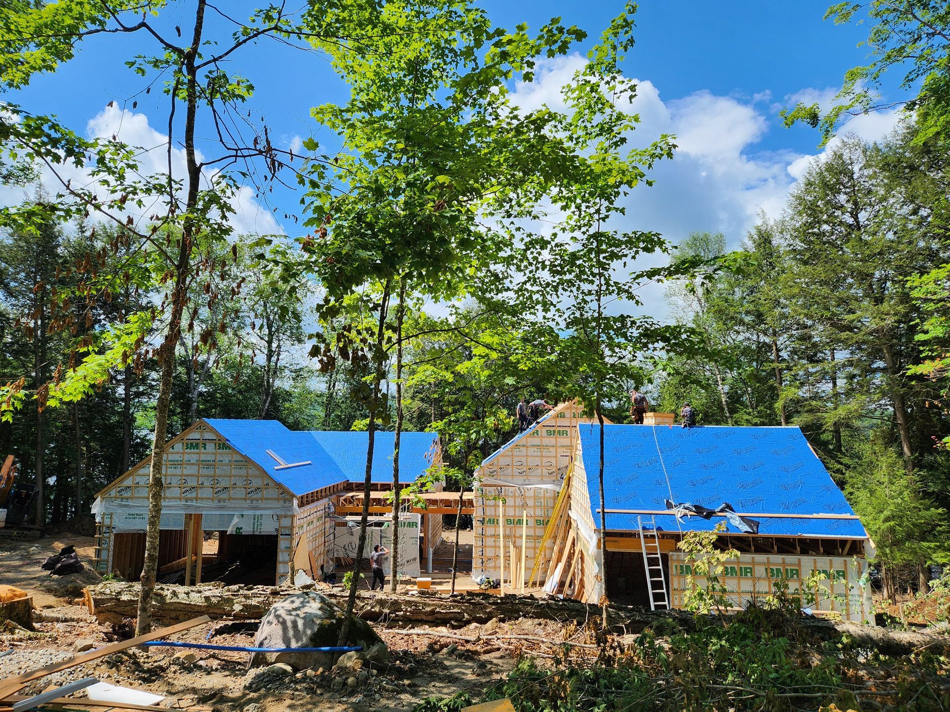 Une maison est en construction dans les bois avec un toit bleu.
